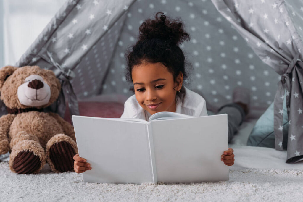 Criança lendo livro espírita infantil em ambiente aconchegante com brinquedo e clima acolhedor