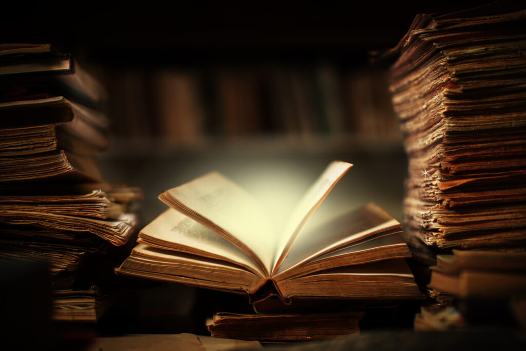 livro aberto representando a literatura espírita com iluminação suave entre pilhas de livros antigos