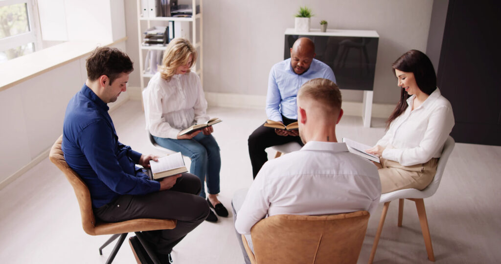 Grupo de estudo lendo livros sobre reencarnação em uma reunião espírita.