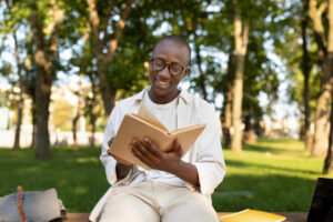 Adolescente lendo livros espíritas infantojuvenis em um parque durante um momento de estudo e reflexão.