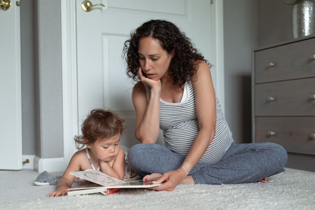 Mãe grávida lê livro infantil com a filha em momento de aprendizado sobre a doutrina espírita.