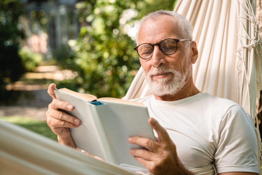 Homem lendo um dos livros espíritas durante momento tranquilo de reflexão ao ar livre.