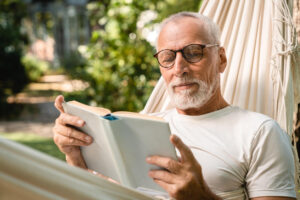 Homem lendo um dos livros espíritas durante momento tranquilo de reflexão ao ar livre.